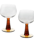 Two clear stemmed glasses with ribbed amber-brown stems and round clear bases, shown on a white background.