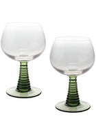 Two clear stemmed glasses with ribbed green stems and circular bases, photographed on a plain white background.