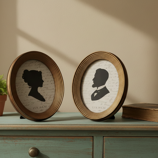 Two oval frames with silhouette portraits on a wooden surface.