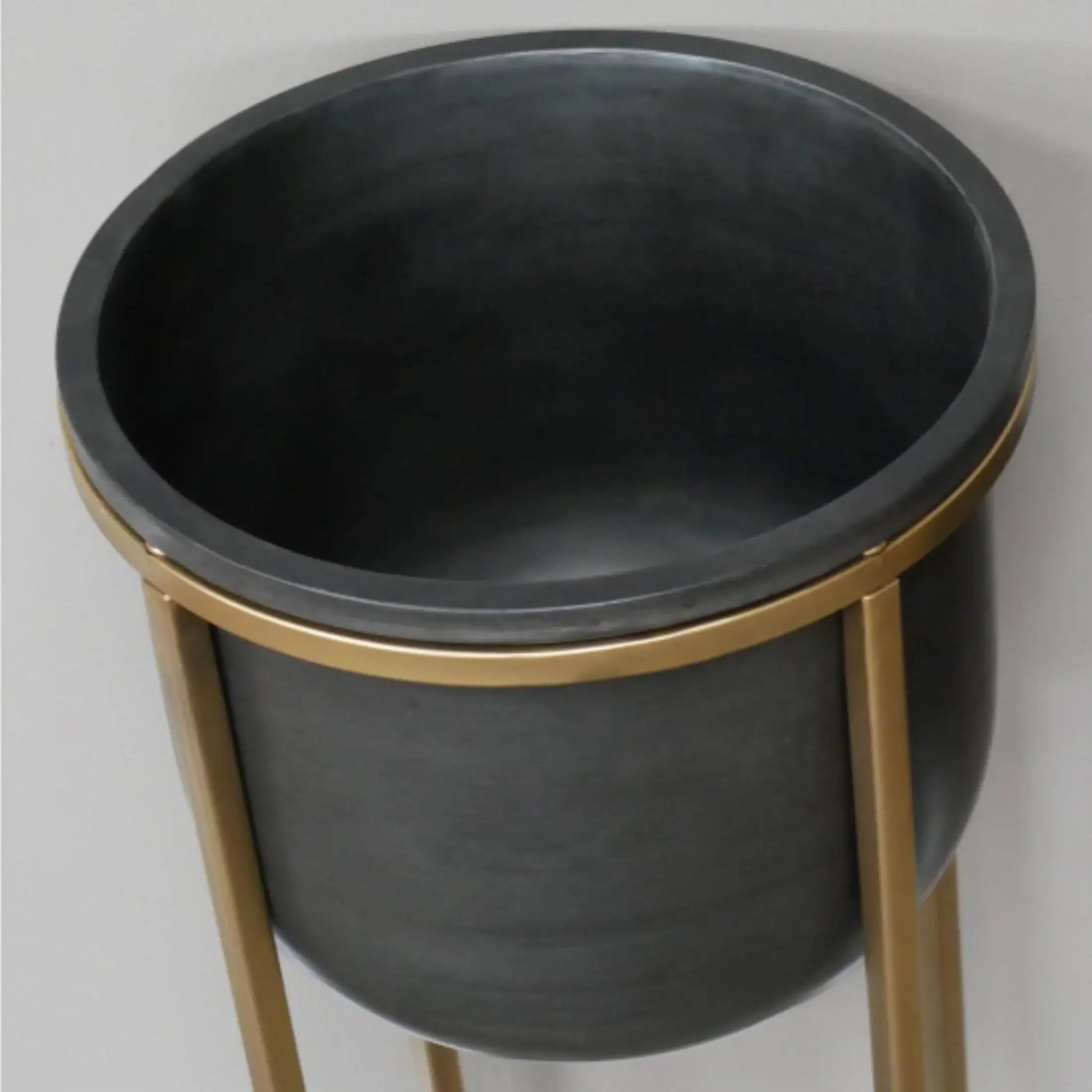 Black planter with gold stand on a light gray background