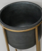 Black planter with gold stand on a light gray background