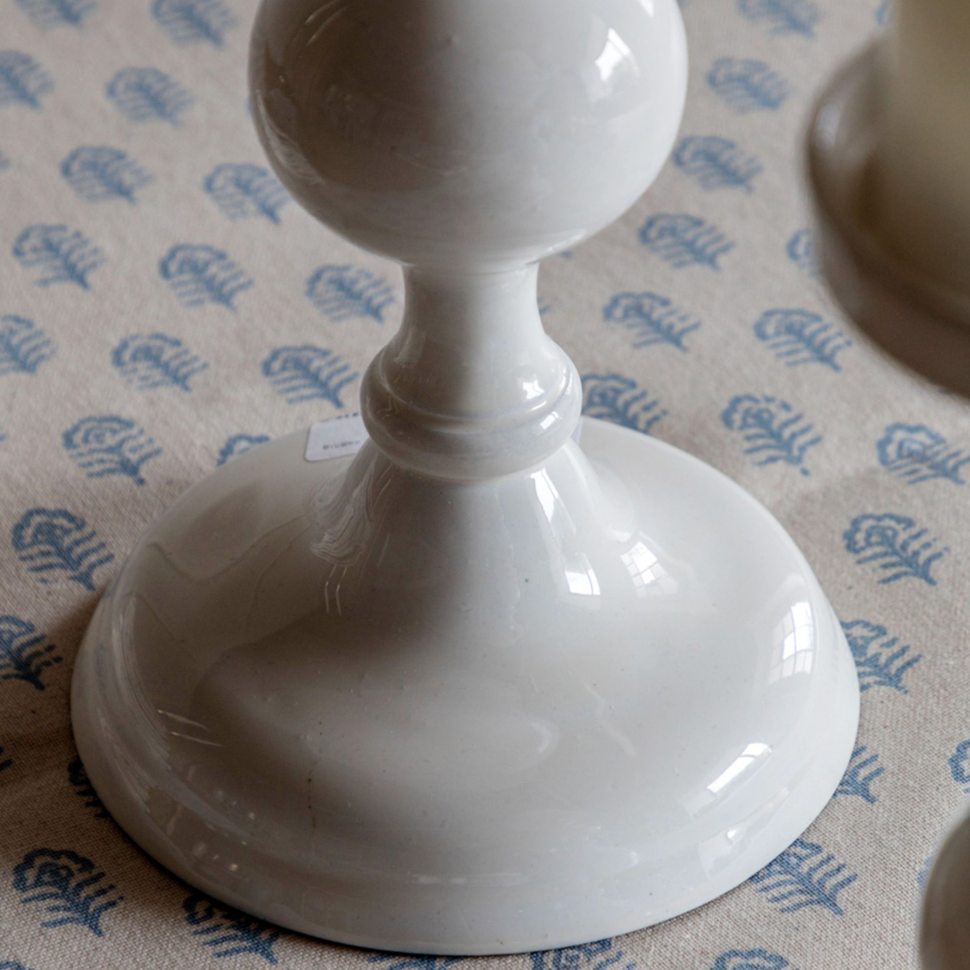 White ceramic candlestick on a patterned surface