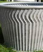 Decorative gray planter with wavy texture on grass