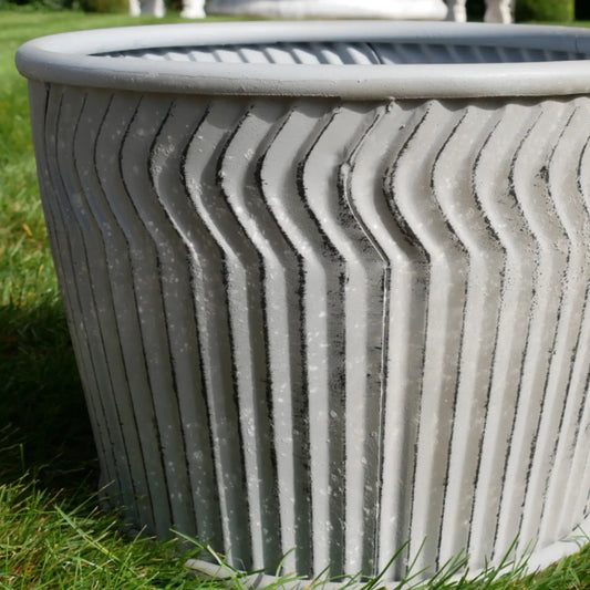 Decorative gray planter with wavy texture on grass