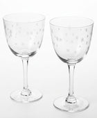 Two clear wine glasses with white star etchings, displayed in front of their brown cardboard packaging box on a white background.