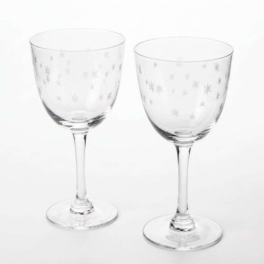 Two clear wine glasses with white star etchings, displayed in front of their brown cardboard packaging box on a white background.