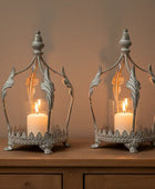 Two ornate candle lanterns on a wooden surface with a neutral background