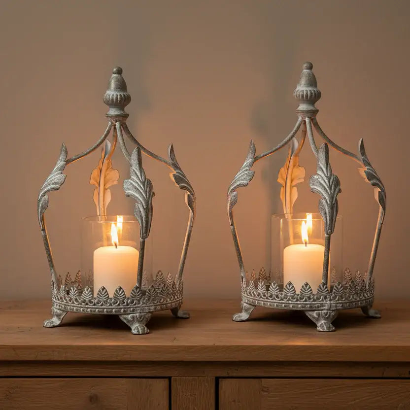 Two ornate metal candle holders with lit candles on a wooden surface.