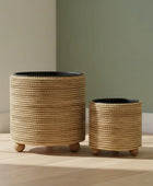 Two woven planters on wheels against a neutral wall.