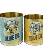 Two decorative metal olive oil tins on a white background. The left tin has a light blue label with an olive branch and bottle illustration, and the right tin has a yellow label with a colorful bird and olive branch illustration.