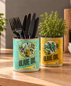 Two decorative metal canisters labeled 'Olive Oil' used as kitchen utensil holders, filled with wooden spoons and a white whisk, on a kitchen counter.