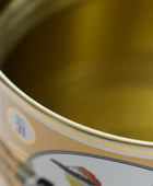 Close-up of the interior of a gold-colored metal tin can with a partially visible label featuring a fish illustration.