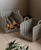 Two wicker baskets on a wooden floor with one containing logs.