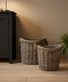 Two wicker baskets on a wooden floor next to a dark cabinet.