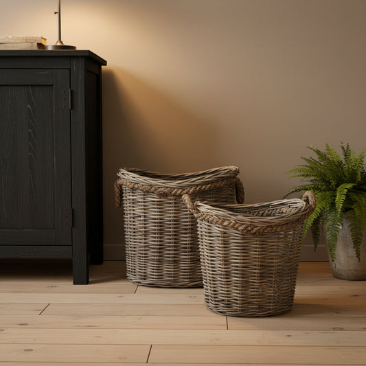 Two wicker baskets on a wooden floor next to a dark cabinet.