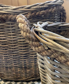 Two wicker baskets with handles on a checkered floor.