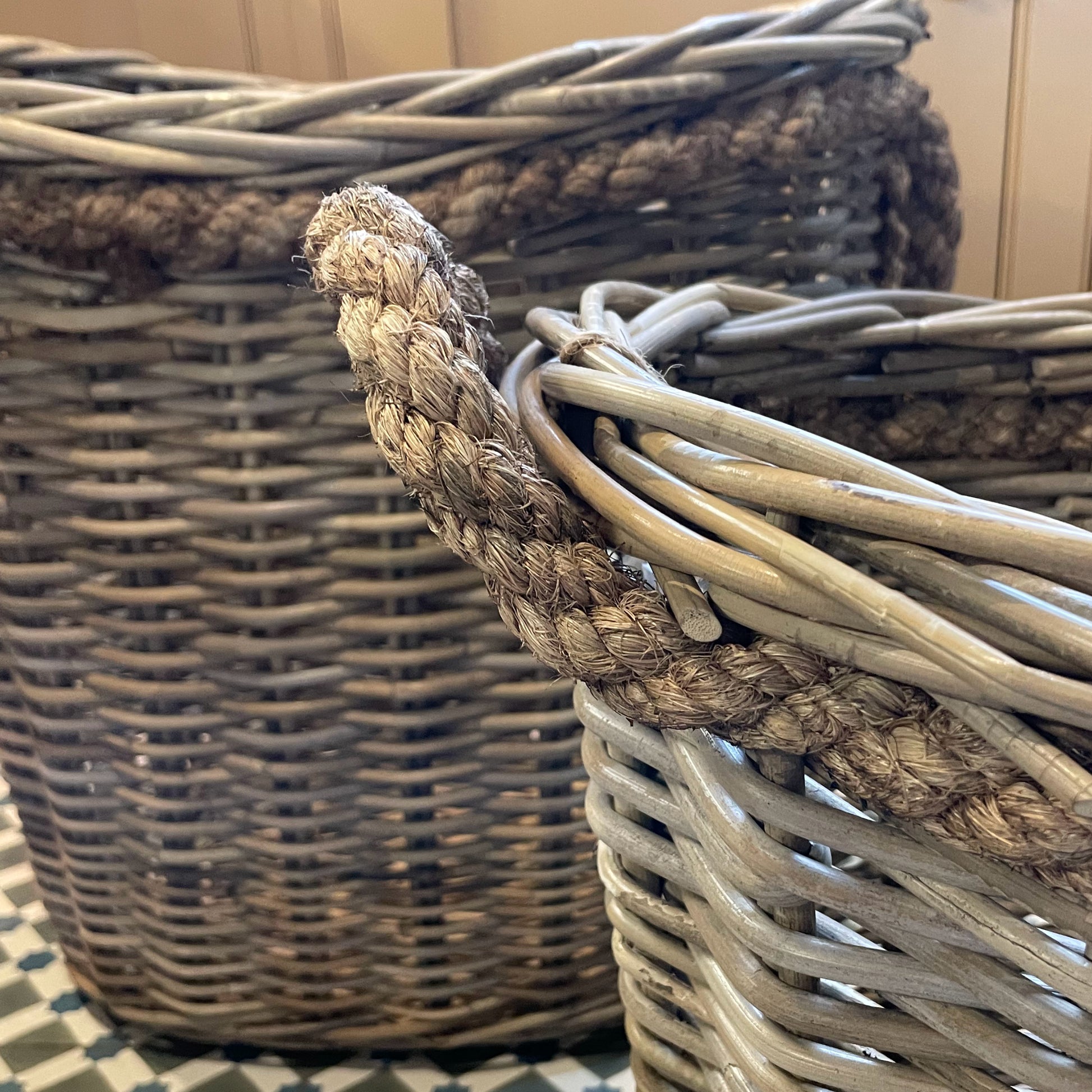 Two wicker baskets with handles on a checkered floor.