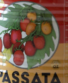Close-up of a packaged food product label featuring an illustration of red and yellow cherry tomatoes on a vine with green leaves, above the word PASSATA.