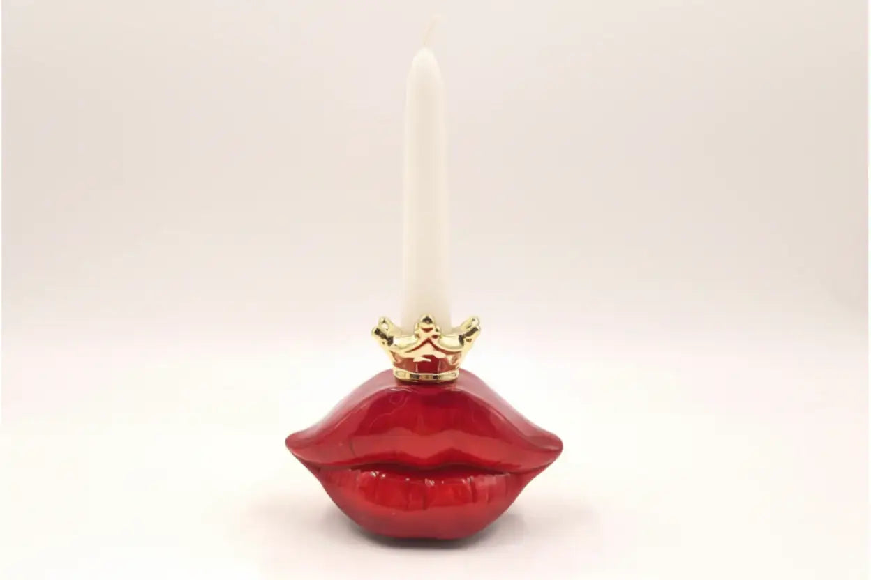 Red lip-shaped candle holder with a white candle on a light beige background