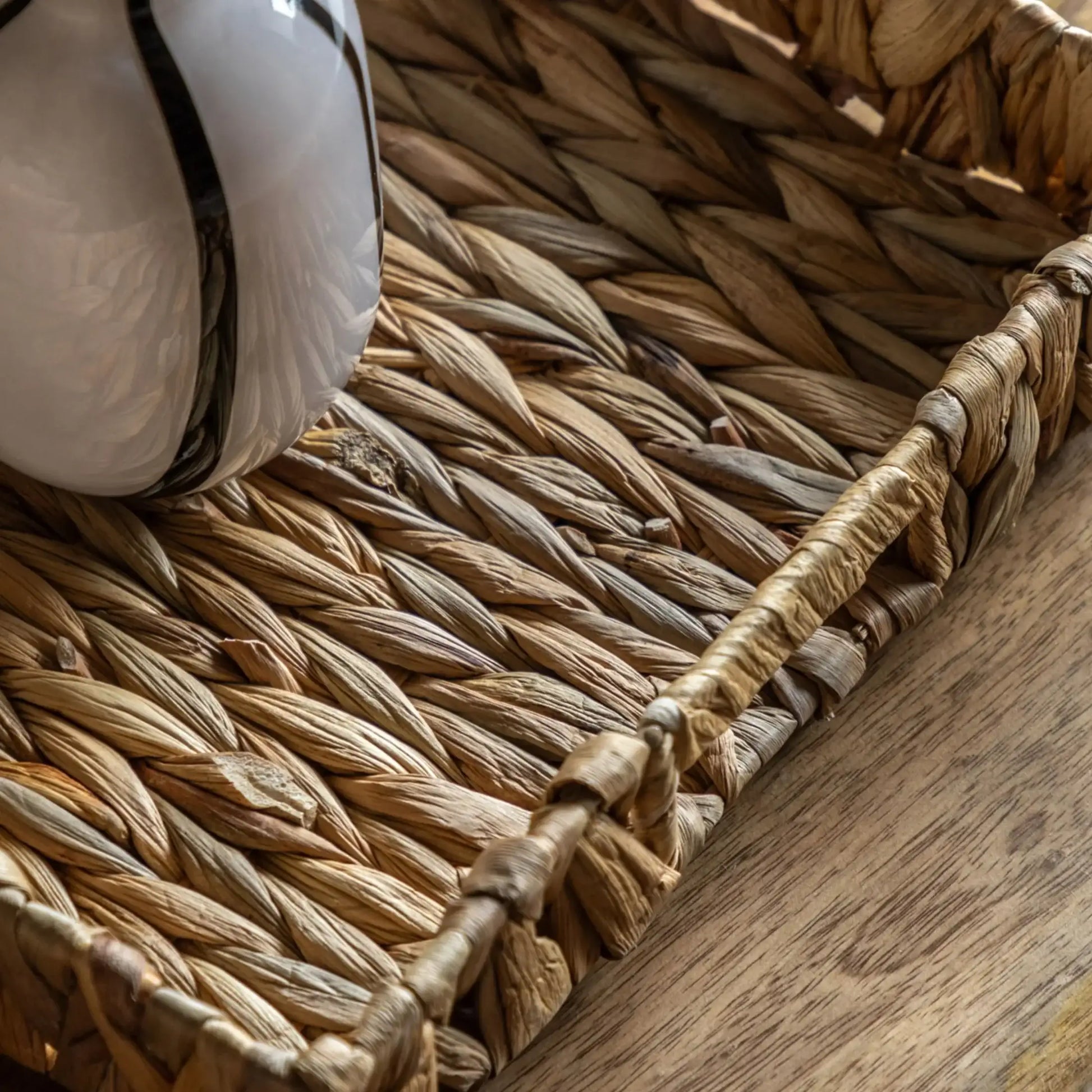 Close-up of a woven basket with a white object inside on a wooden surface