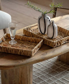 Decorative setting with wicker trays and vases on a wooden table.