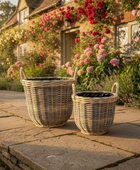 Two wicker baskets on a stone patio with a garden and house in the background