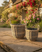 Wicker planters on a stone patio with a house and garden in the background