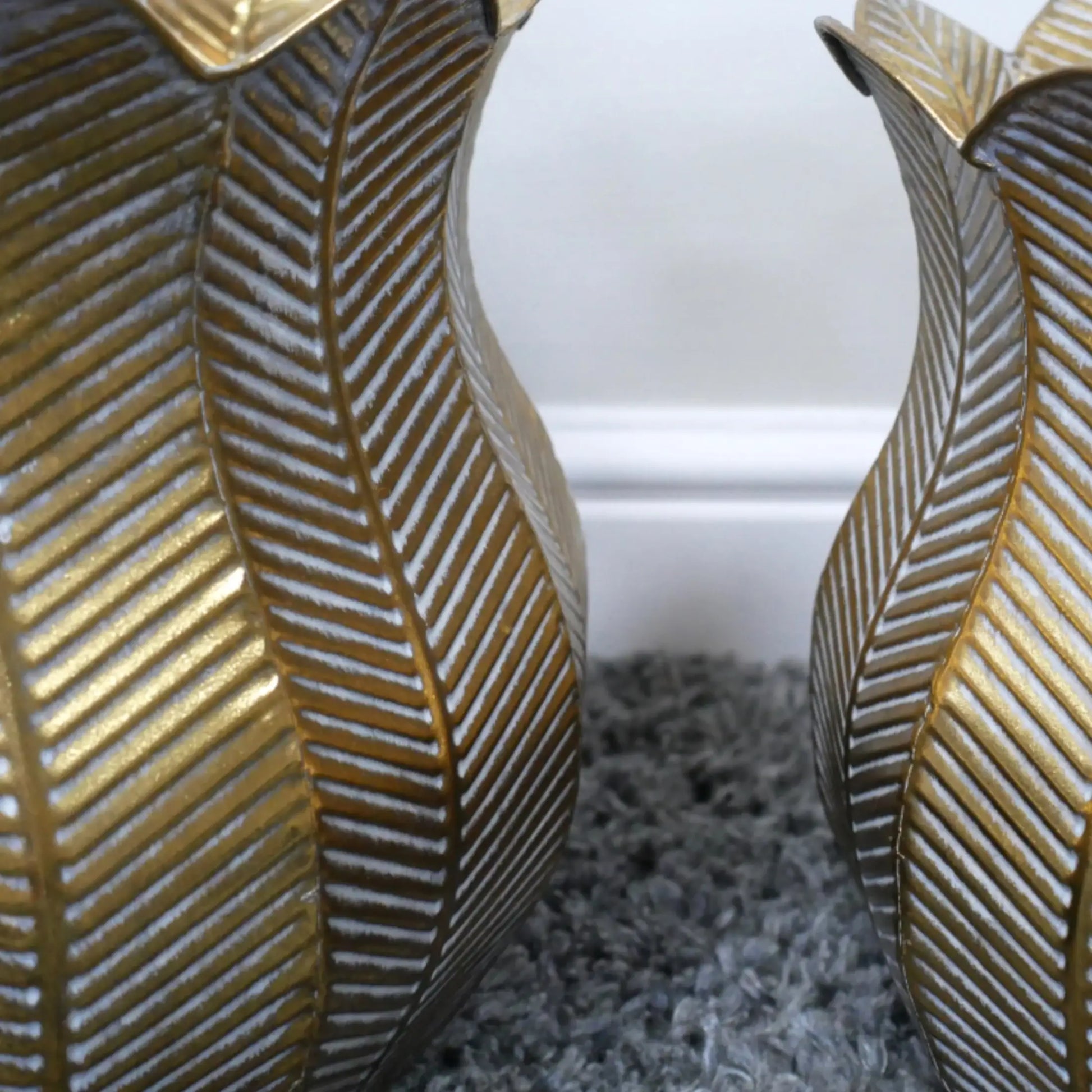 Two decorative vases with gold leaf pattern on a textured surface