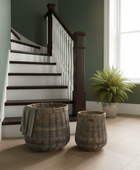 Staircase with wicker baskets and a plant in a room with green walls and a window.
