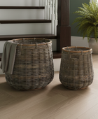 Two wicker baskets on a wooden floor with a staircase and plant in the background.