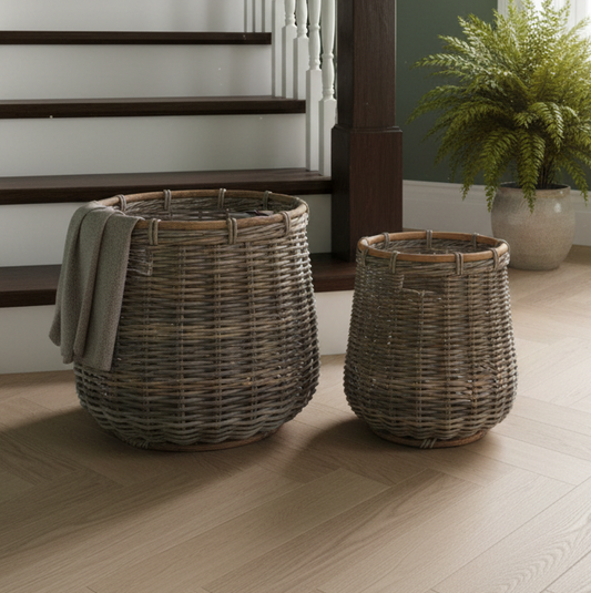 Two wicker baskets on a wooden floor with a staircase and plant in the background.