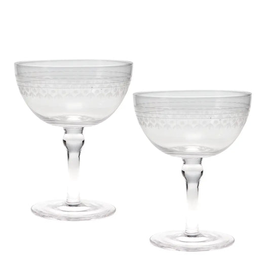 Two clear glass coupe glasses with etched geometric patterns on the bowls and stems, shown on a plain white background.