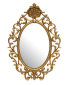 An ornate oval wall mirror with an elaborate gilded baroque-style frame featuring scrollwork and a decorative crest at the top, shown against a plain white background.