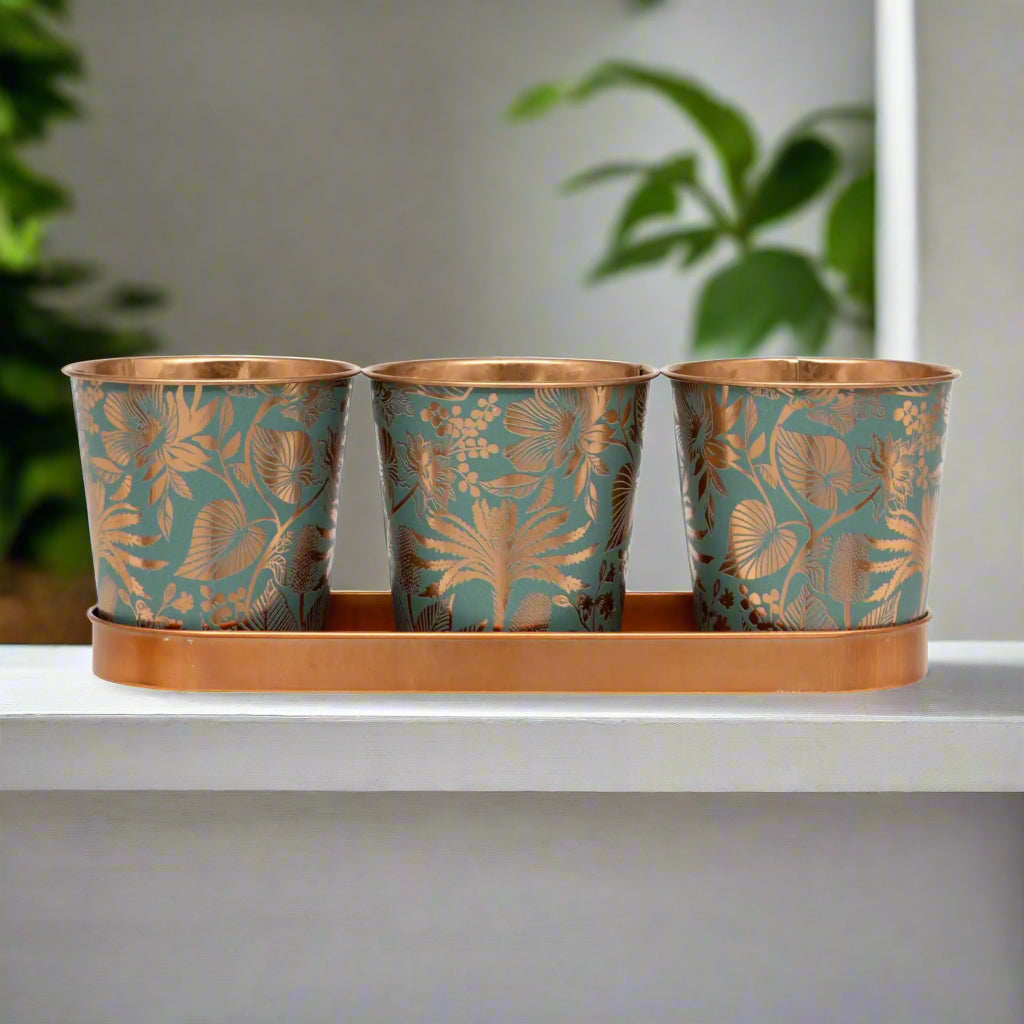Three decorative metal pots with floral patterns on a matching tray.