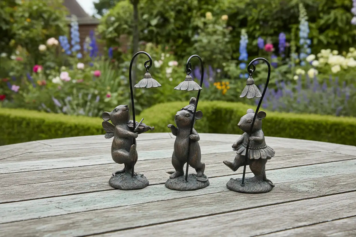 Three decorative mouse figures with lampshades on a wooden surface with a garden background.