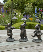 Three decorative mouse statues with lampshades on a wooden surface with a garden background.