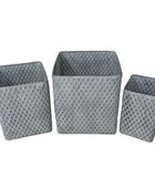 Three gray woven baskets of different sizes on a wooden surface with a neutral background