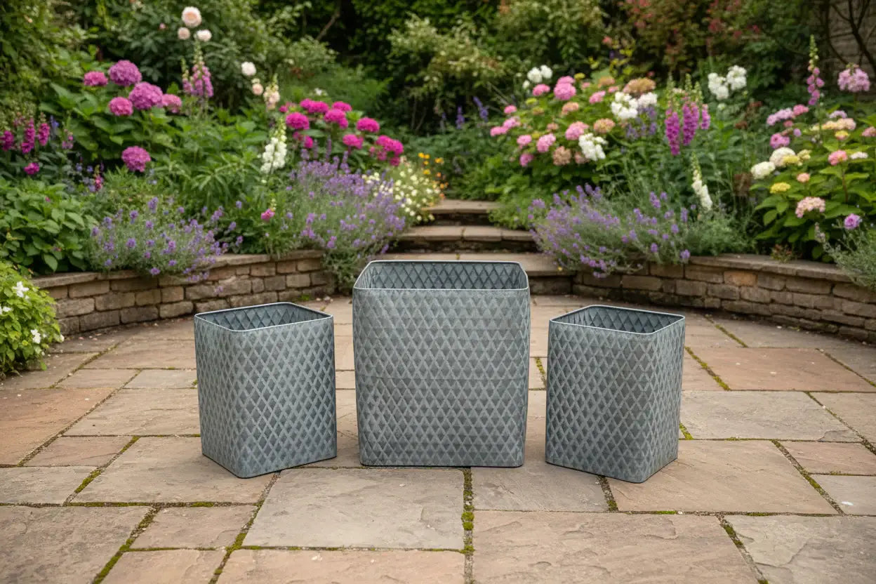 Three gray woven planters on a stone patio with a garden in the background