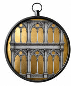 A circular pendant or medallion featuring a Gothic-style arch pattern in gray over a textured gold background, enclosed in a black metal frame with a hanging loop at the top, shown on a plain white background.