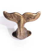 Bronze whale tail decorative item on a white background