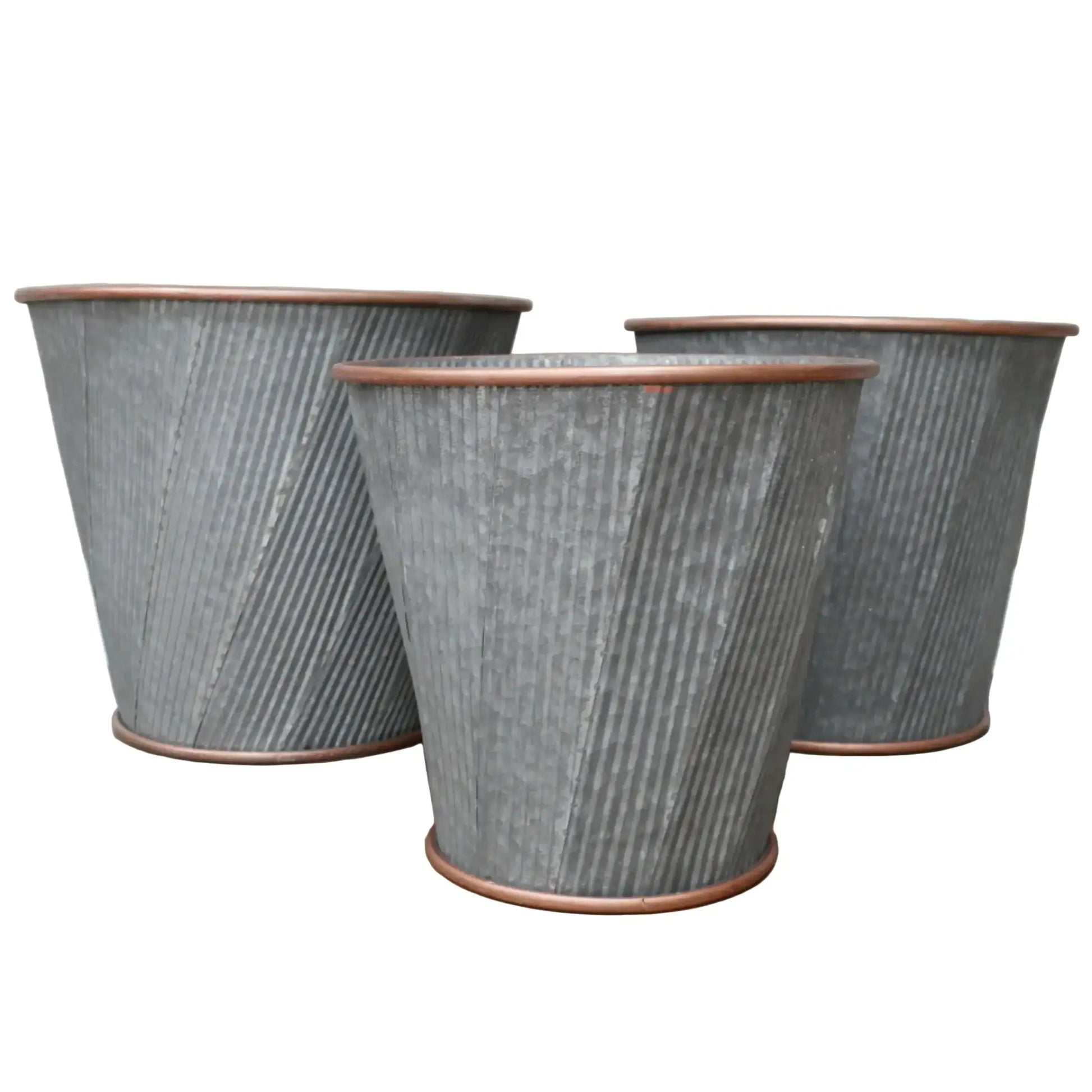 Three textured metal planters on a wooden floor with a neutral background