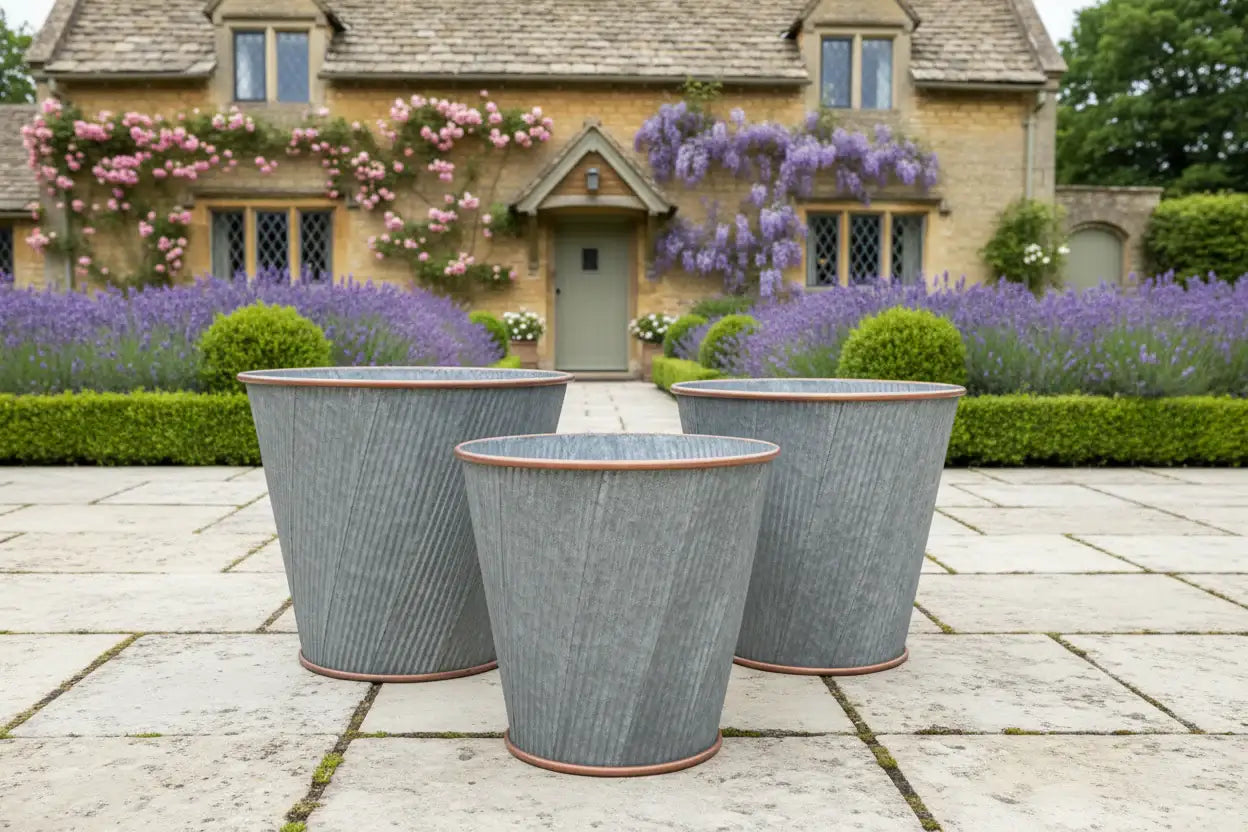 Three decorative planters on a stone patio with a house and garden in the background