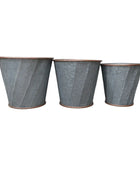 Three textured metal planters on a wooden surface with a neutral background