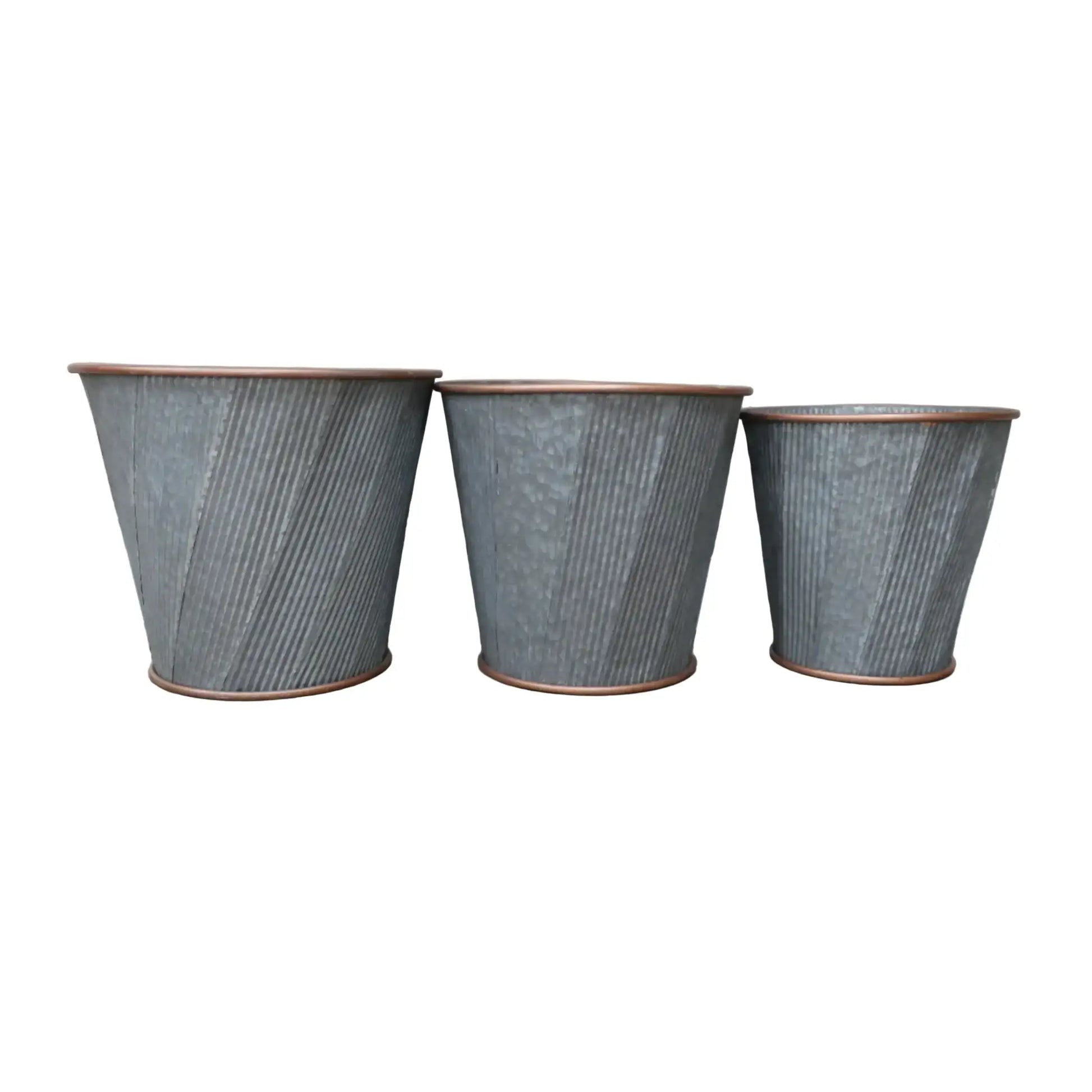 Three textured metal planters on a wooden surface with a neutral background