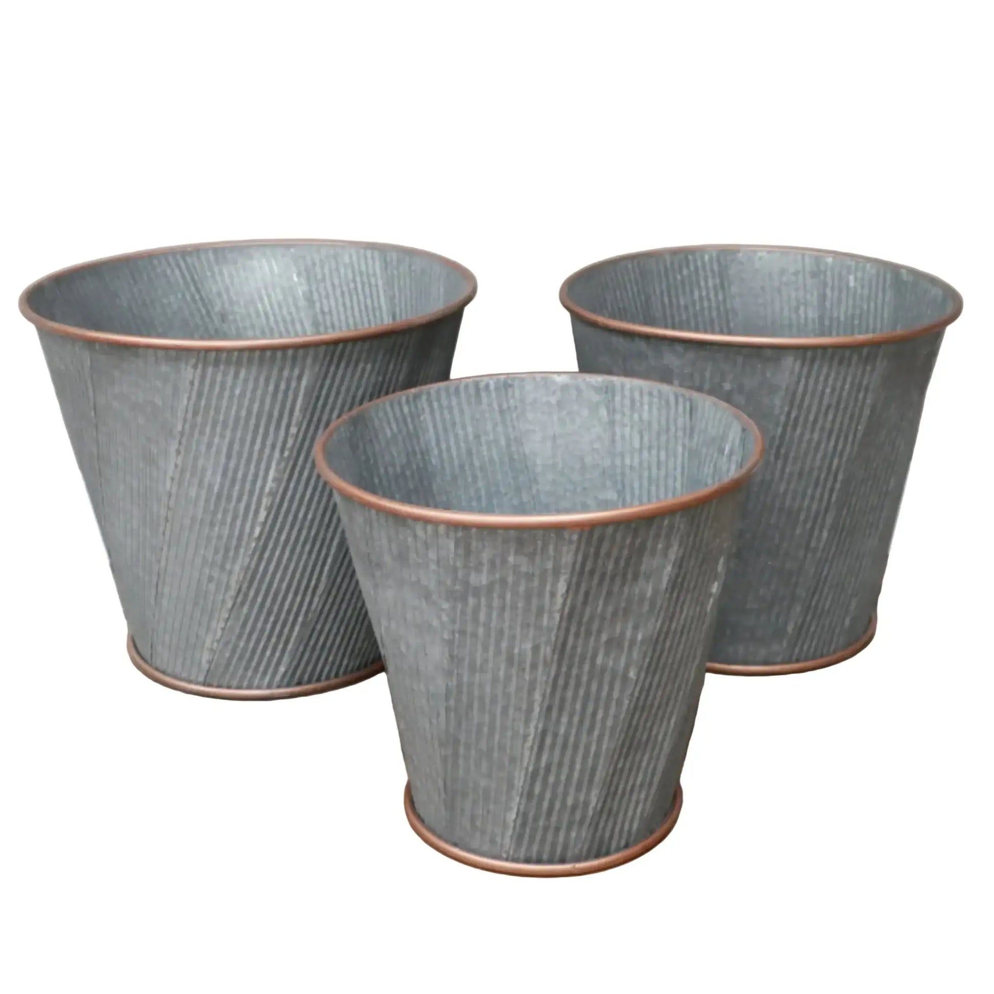 Three textured metal planters on a wooden surface with a neutral background