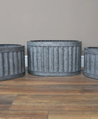 Three metal planters with a ribbed texture on a wooden surface.