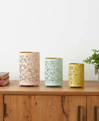 Three decorative candles with floral patterns on a wooden surface.