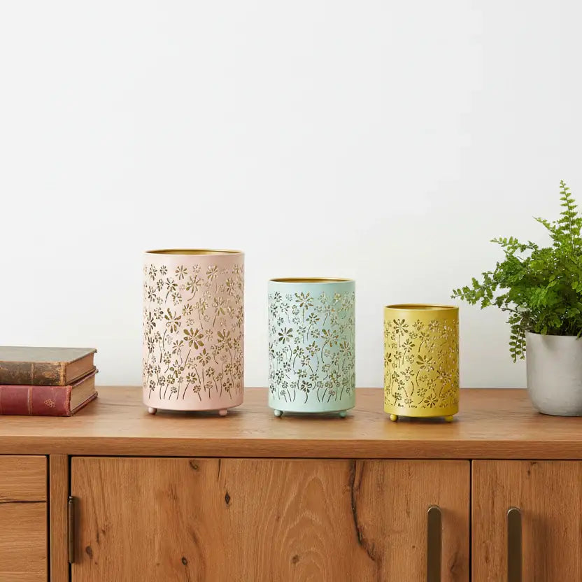 Three decorative candles with floral patterns on a wooden surface.