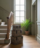 Stack of wicker baskets on a wooden floor with a staircase and window in the background
