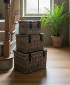 Stack of wicker baskets on a wooden floor with a plant in the background